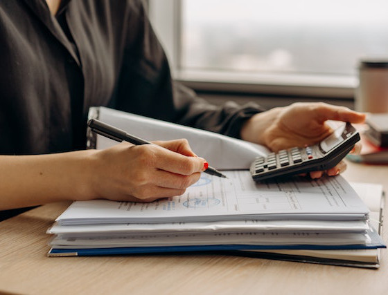 mujer cumplimentando documento y con calculadora en la mano